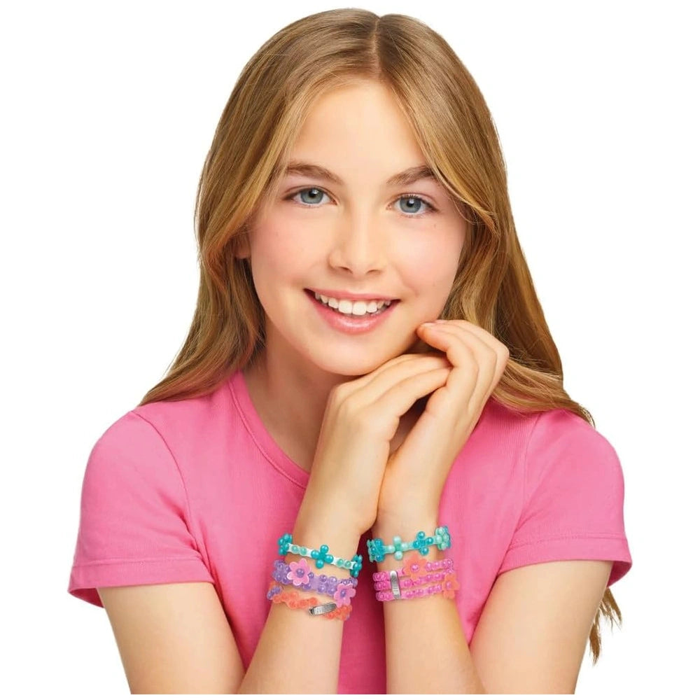 LINXO Seaside Jewelry Design Set showcased by a smiling girl in a pink t-shirt, wearing multicolored bracelets, against a whi