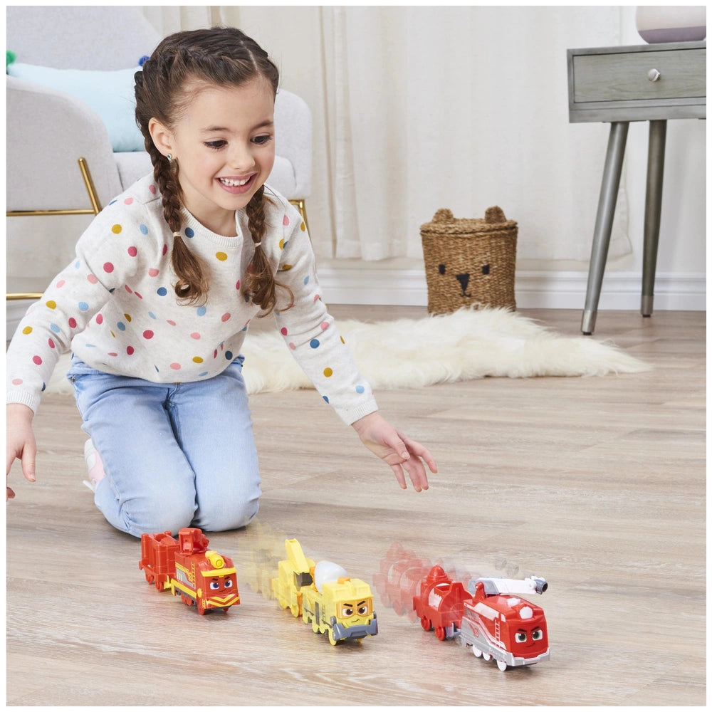 Mighty Express Motorized Train set with colorful plastic trains, as a young girl plays joyfully on light wood flooring.