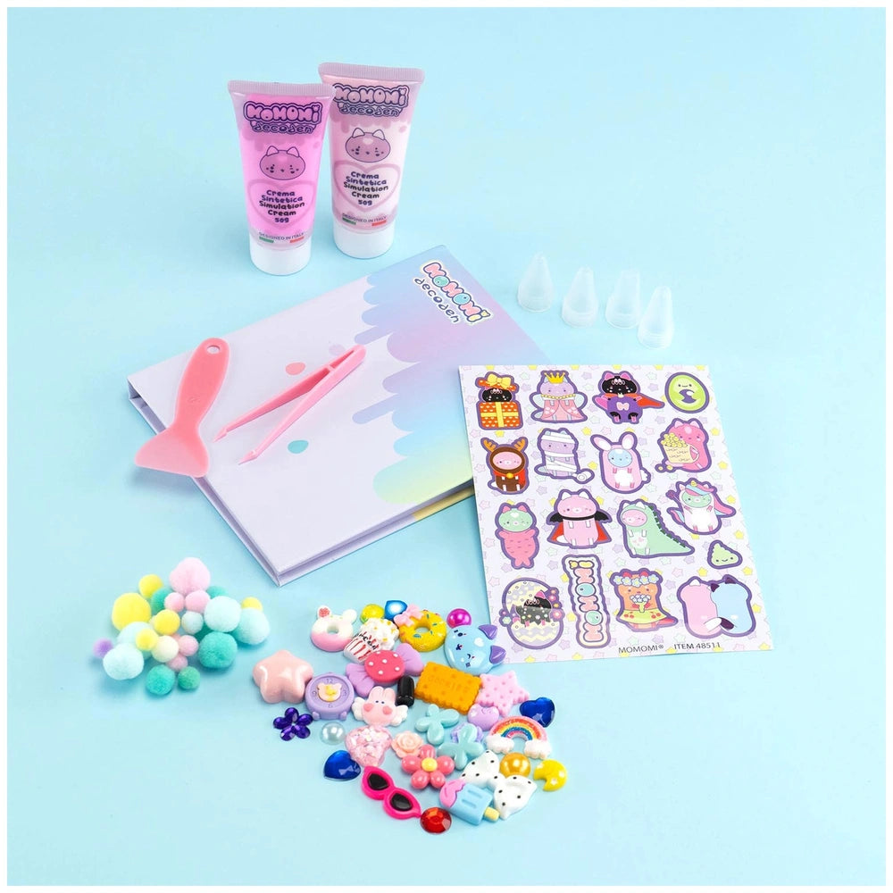 Momomi Decoden Kawaii Arts & Crafts Kit packaging featuring pink and white cream tubes, colorful booklet, and multiple plasti