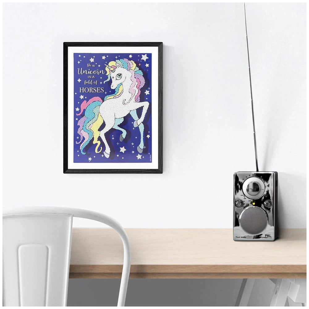 Nice Diamantiny Crystal Art Design Set displayed on a light wood desk with a black-framed unicorn picture and silver radio.