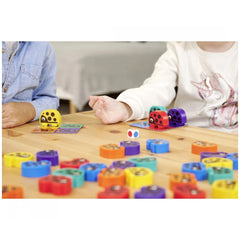 Noris - 3 Colorful Bug Games showing children playing with vibrant game pieces on a wooden surface in a casual setting.