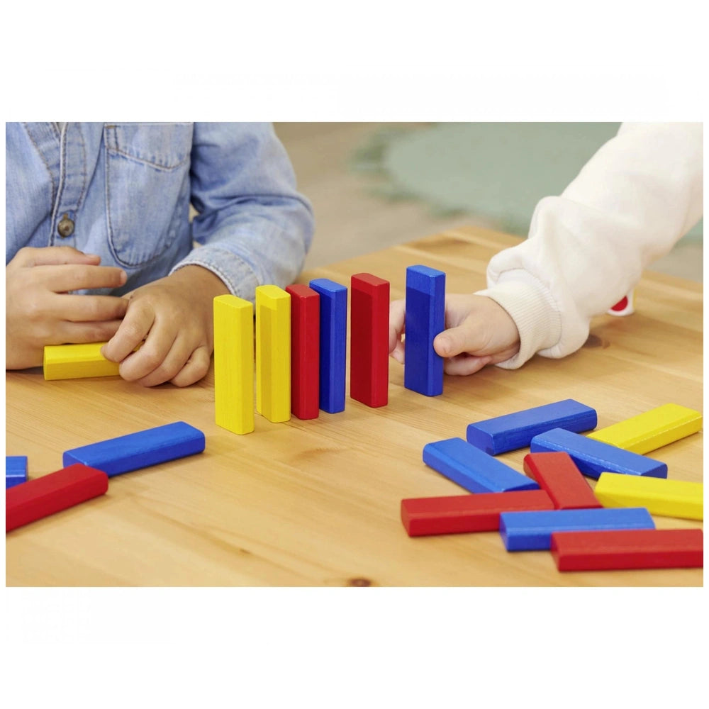 Noris colorful building block games with children placing blue and red blocks on a light wooden surface indoors.