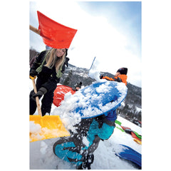Igloo Comfort Shovel for Kids in red and yellow, with two people playing in snow, featuring a blue snowboard and winter gear.