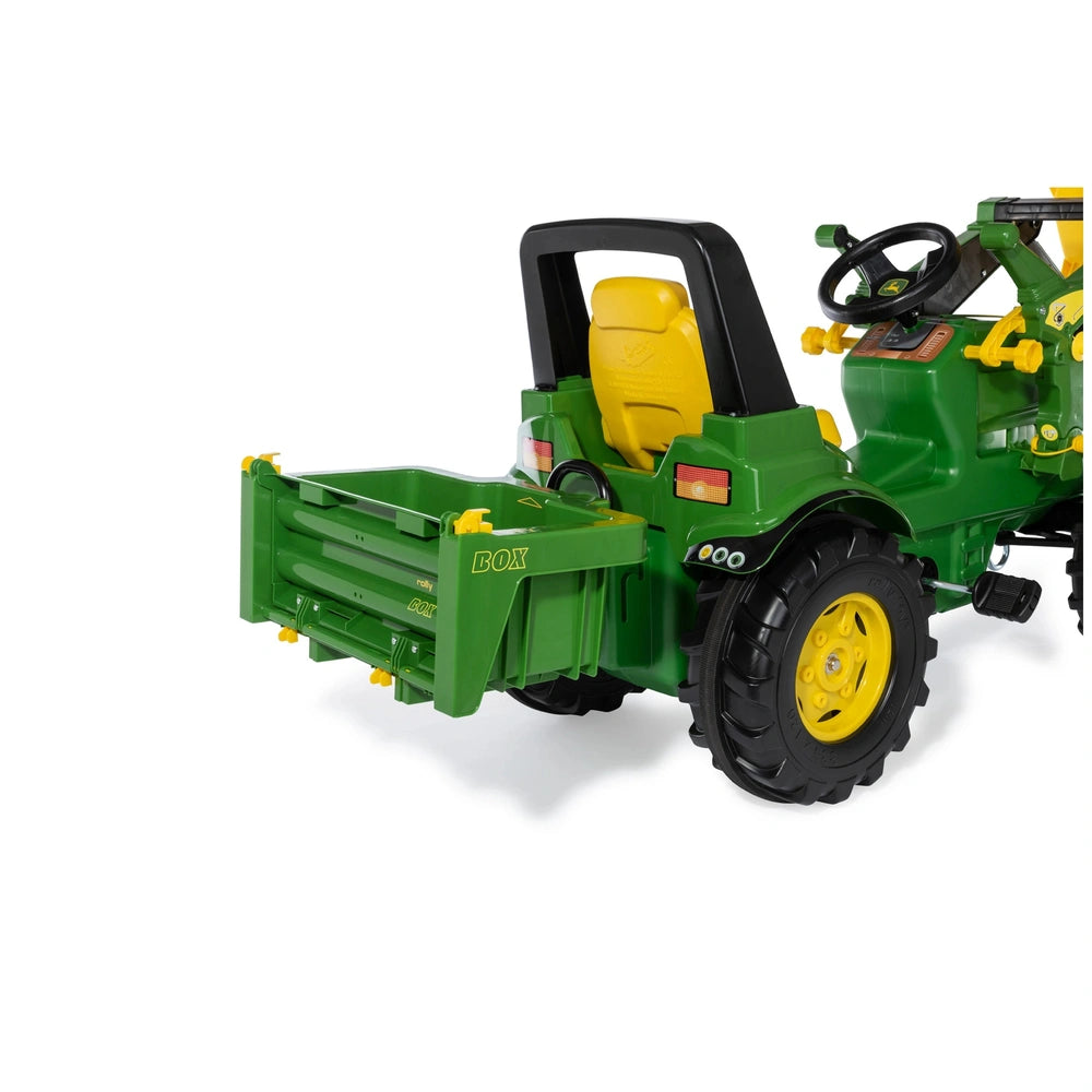 Green toy tractor with yellow accents, black seat, and large black wheels, featuring a front loader bucket attachment.
