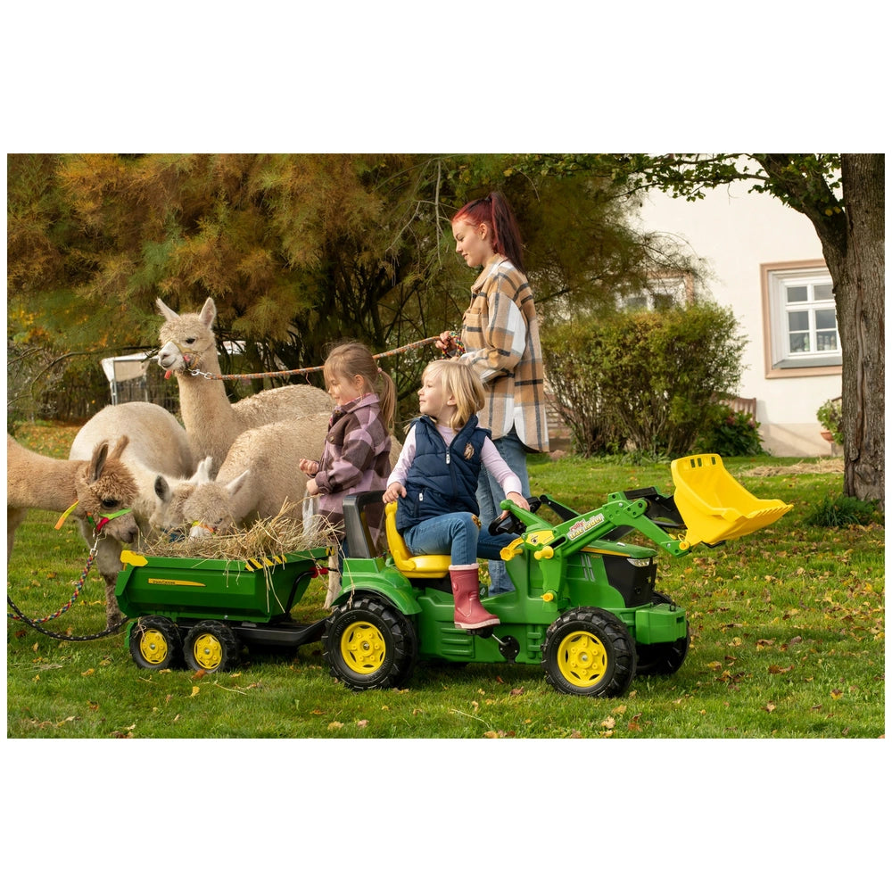 Rollyhalfpipe John Deere Trailer is showcased in an outdoor scene with a woman, girl, and a calm llama on grass.