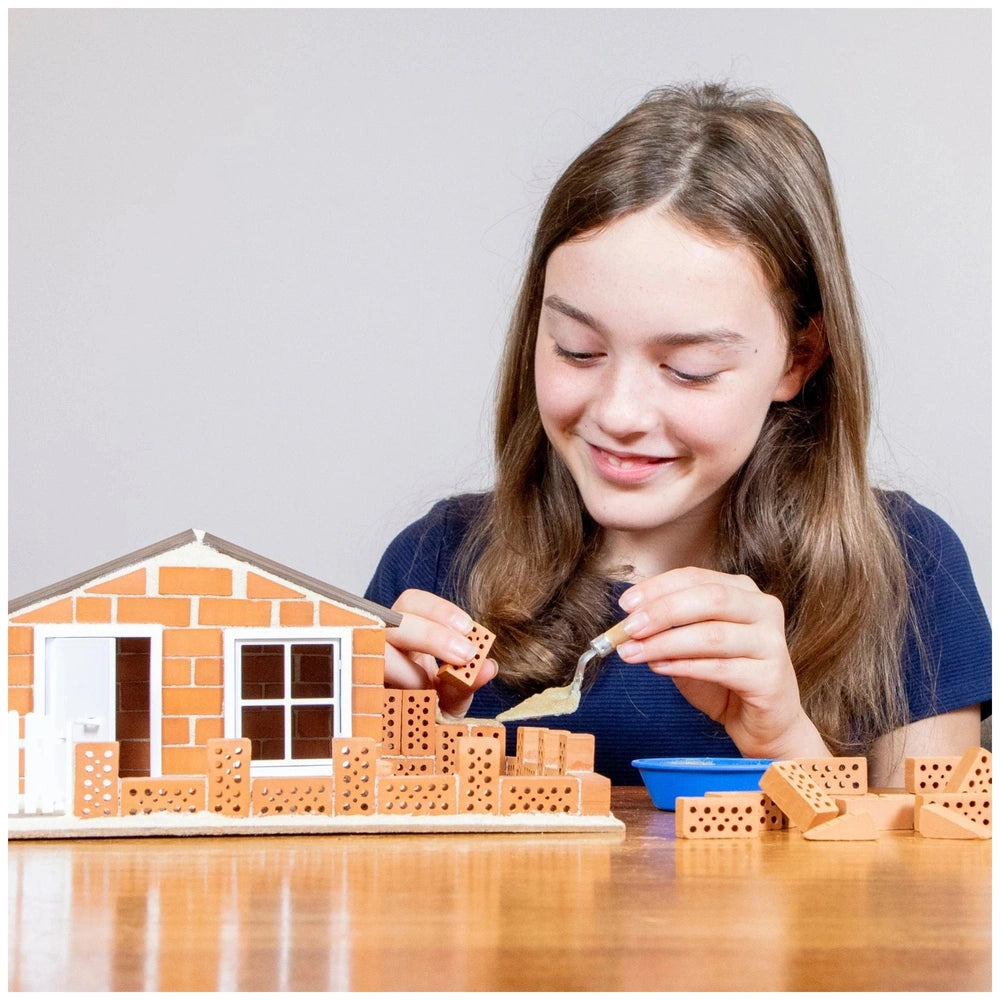 Teifoc beach house craft set features a smiling girl with brown hair, engaged with orange Lego-like building blocks.