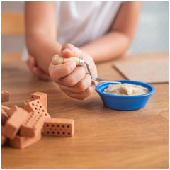 Teifoc doghouse kit includes a wooden rolling pin and spoon held by hands on a wooden surface with scattered cylindrical piec