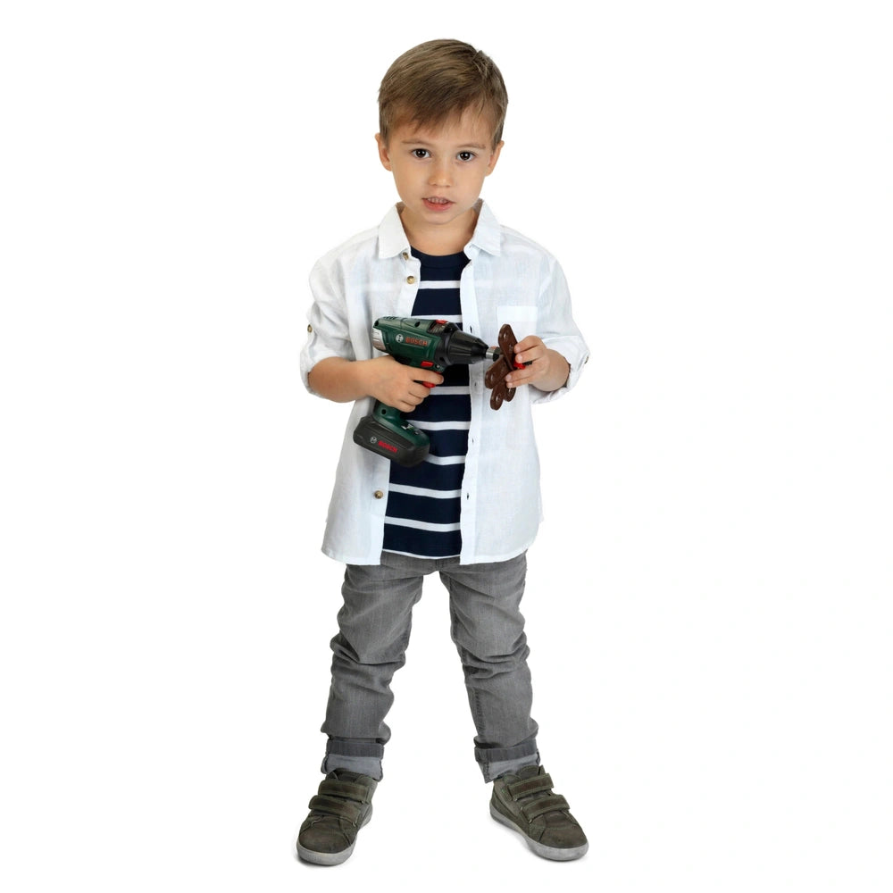 Theo Klein Bosch cordless drill and screwdriver held by a child in a white striped shirt and gray pants, with brown hair.