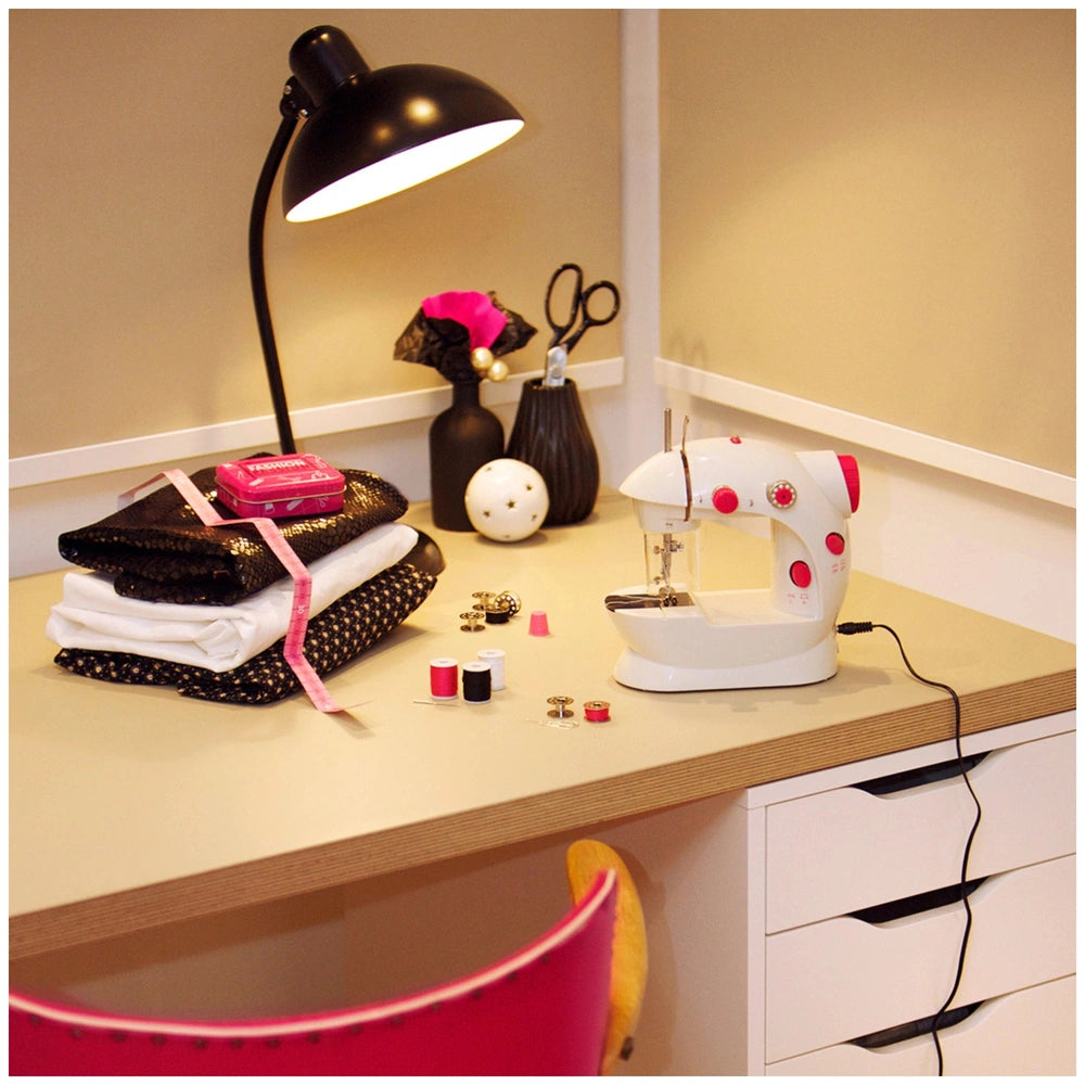 Theo Klein kids sewing machine on a wooden desk with various colorful fabrics, including pink, black, and white patterns.
