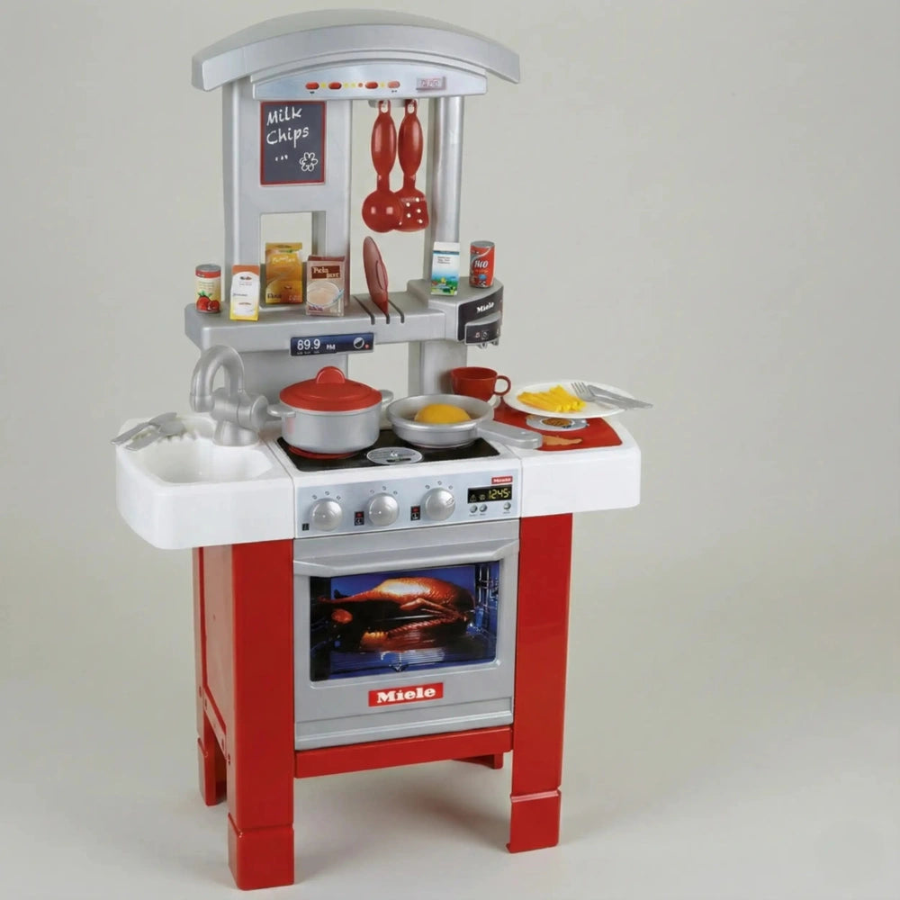 Theo Klein Miele kitchen starter set featuring a red plastic oven with silver knobs, buttons, and a clear window.