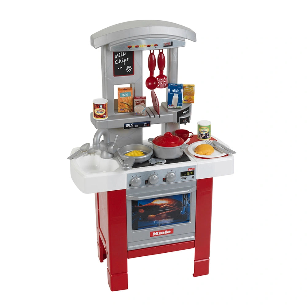 Miele kitchen starter set featuring a red plastic countertop, white and gray oven with clear window, and silver knobs.